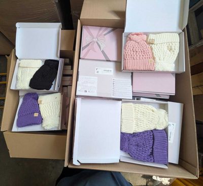 Plusieurs cartons contenant des bonnets et des écharpes tricotés sont empilés les uns sur les autres