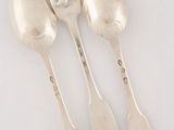 three silver spoons and a fork on a white surface