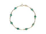 un bracelet en or orné de perles de verre vertes sur fond blanc