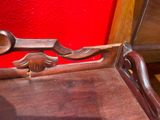 a close up of a wooden chair with a red wall