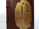 an old book with a gold design on it sitting on a white surface