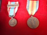 two medals are sitting on a red cloth with a ribbon around them