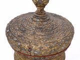 a gold and red vase with a lid on a white surface
