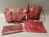 three red leather purses and a wallet sitting on a table