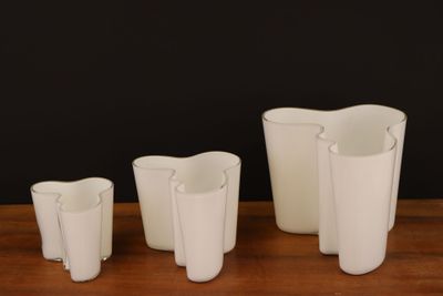 trois vases blancs posés les uns à côté des autres sur une table en bois