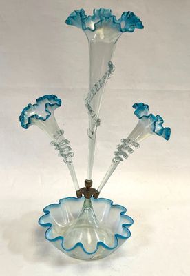 a glass vase with blue flowers in it on a white surface