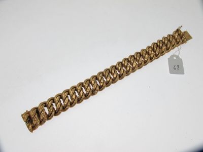 gros plan d'un bracelet en chaîne en or sur une surface blanche