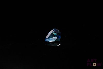 a close up of a blue diamond on a black surface