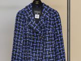 une veste bleue et noire suspendue à un porte-manteau devant un mur beige