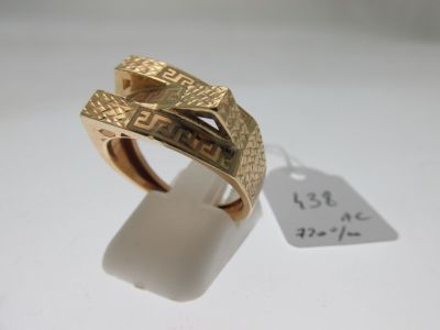 gros plan d'une bague en or sur une surface blanche avec une étiquette de prix
