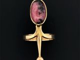 gros plan d'une bague en or avec une pierre rose