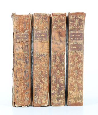trois vieux livres posés l'un sur l'autre sur une surface blanche