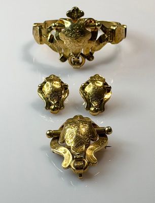 three pieces of gold jewelry sitting on top of a white surface
