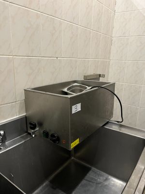 a stainless steel sink in a bathroom with tiled walls