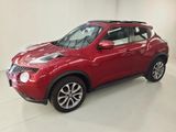 the red nissan juke suv is parked in a white room