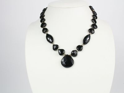 Le collier est composé de perles de verre noires et d'un pendentif en pierre noire.