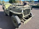 une jeep verte garée sur un parking près d'une clôture