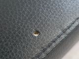 a close up of a black purse with a small hole in it