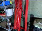 a large red crane in a garage next to a trash can and a trash can