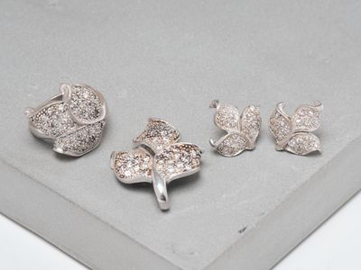 trois bijoux en argent posés sur une surface grise