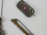 a necklace, a brooch, a pin, and a pair of scissors on a table