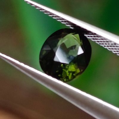 a close up of a green diamond being held by a pair of pliers