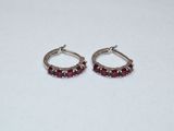a pair of silver hoop earrings with red stones