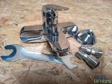 a close up of a faucet with a wrench and other tools on a table