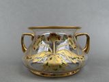 a glass vase with a gold decoration on it