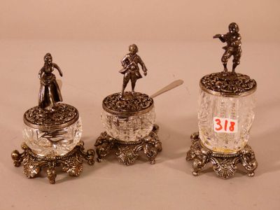 trois figurines en argent représentant des hommes tenant des cuillères et un pot de confiture