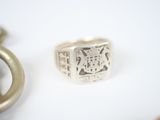 a ring with a coat of arms on it next to a pair of scissors