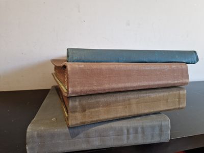trois vieux livres empilés les uns sur les autres sur une table