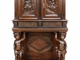 une armoire ancienne en bois ornée de figures sculptées sur le dessus