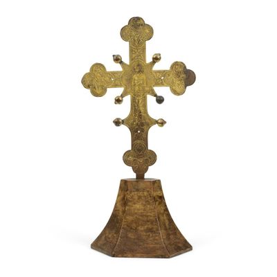 une croix en or posée sur un socle en bois, sur fond blanc