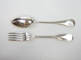 two spoons and a fork on a white table