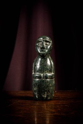 a green stone figurine sitting on top of a wooden table