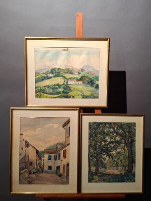 three framed paintings of a village scene on a wooden easel