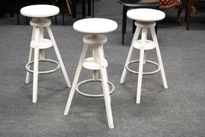 trois tabourets blancs posés sur un sol recouvert de moquette, à côté d'une table