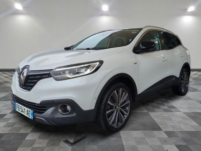 une voiture blanche est garée dans une grande pièce au sol en damier