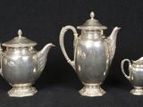 three silver teapots and a sugar bowl on a black background