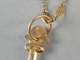 an image of a gold cross necklace with a coin on it