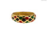 un gros plan d'une bague en or ornée de carrés noirs, rouges et verts