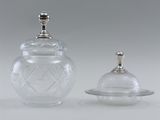 two clear glass jars with silver lids and lids on a table