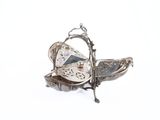 a silver plate with a butterfly on it on a white surface