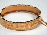 a close up of a gold bracelet on a white surface