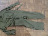 a green suit laying on the floor next to a pair of shoes