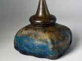 a blue and brown vase sitting on a white surface
