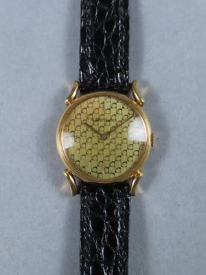 une image représentant une montre en or avec un bracelet noir