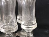 three clear glass goblets sitting on top of a black table