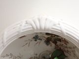a white vase with a green flower inside of it